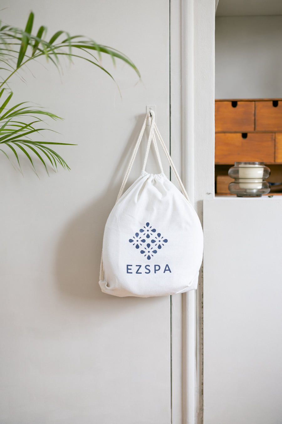 La bolsa de transporte de algodón de Ezspa con el logotipo, colgada en un dormitorio
