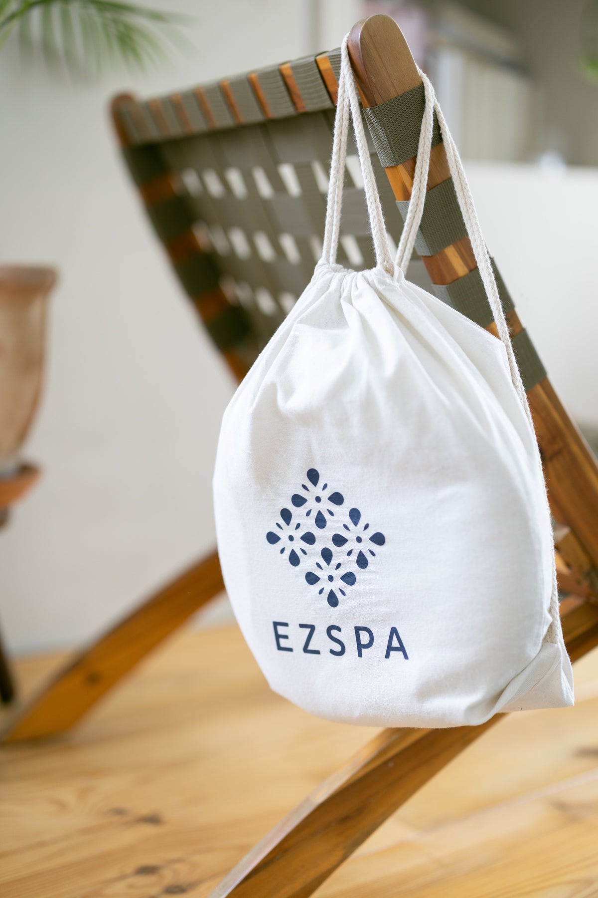 La bolsa de transporte de algodón de Ezspa con el logotipo, colgada de una silla