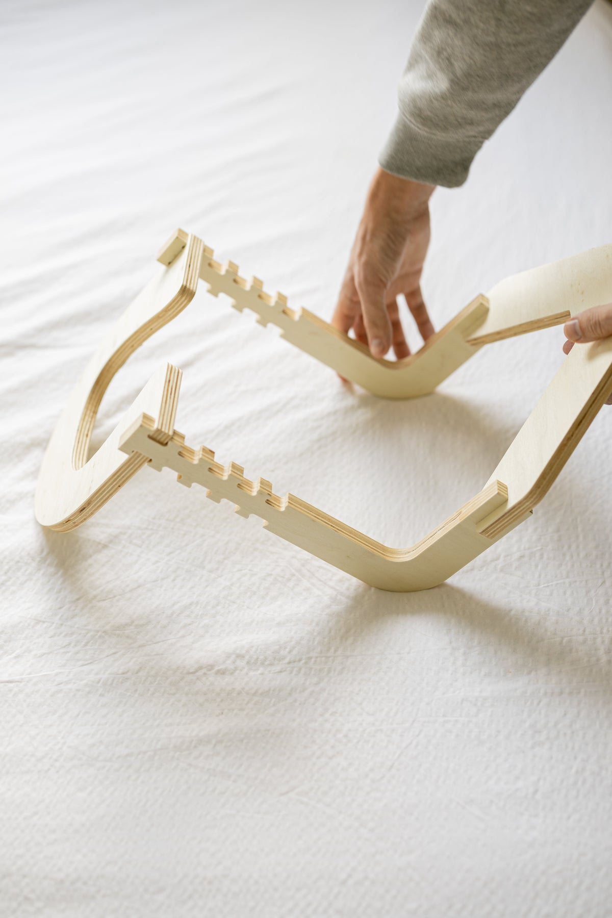 Unas manos montan el marco de madera sobre una cama hecha