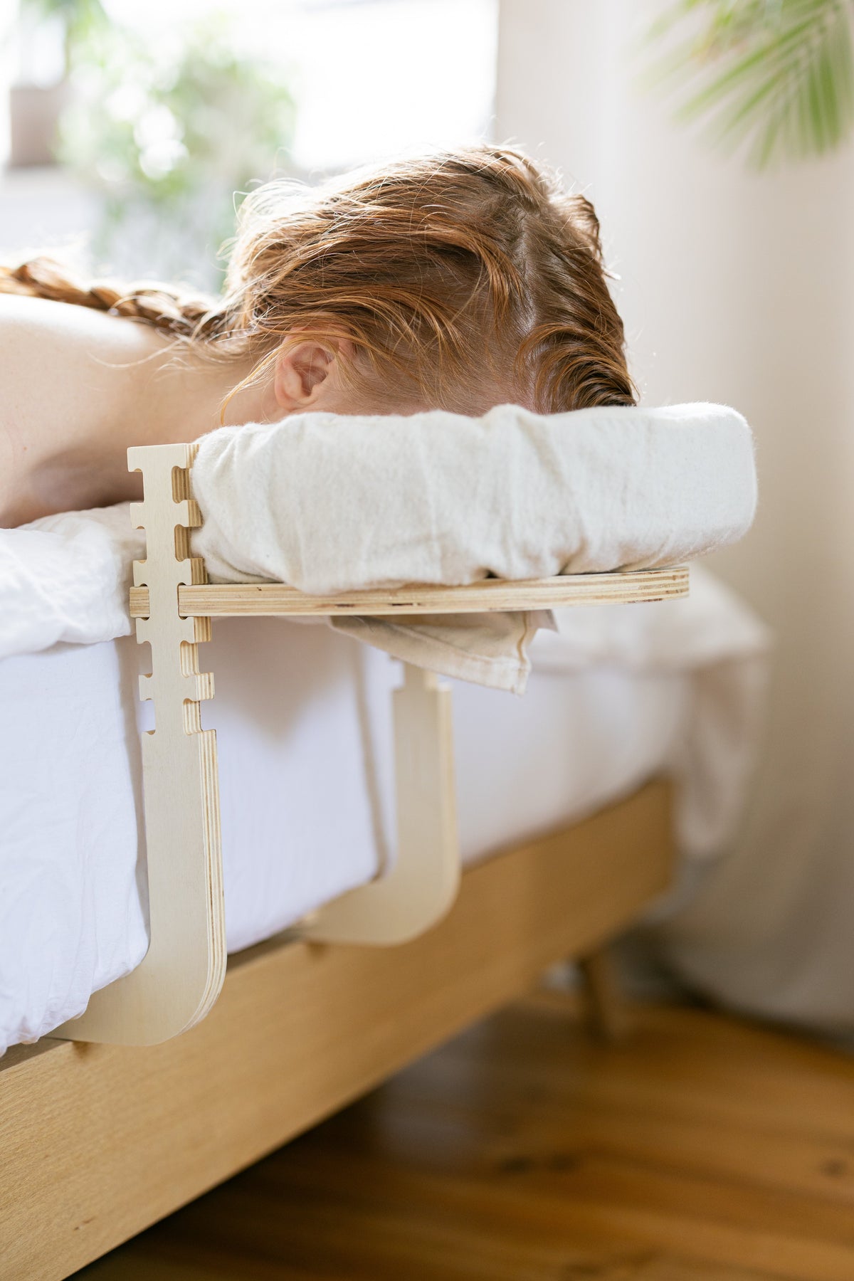 Mujer con trenza tumbada con la cabeza en el reposacabezas en el borde de la cama