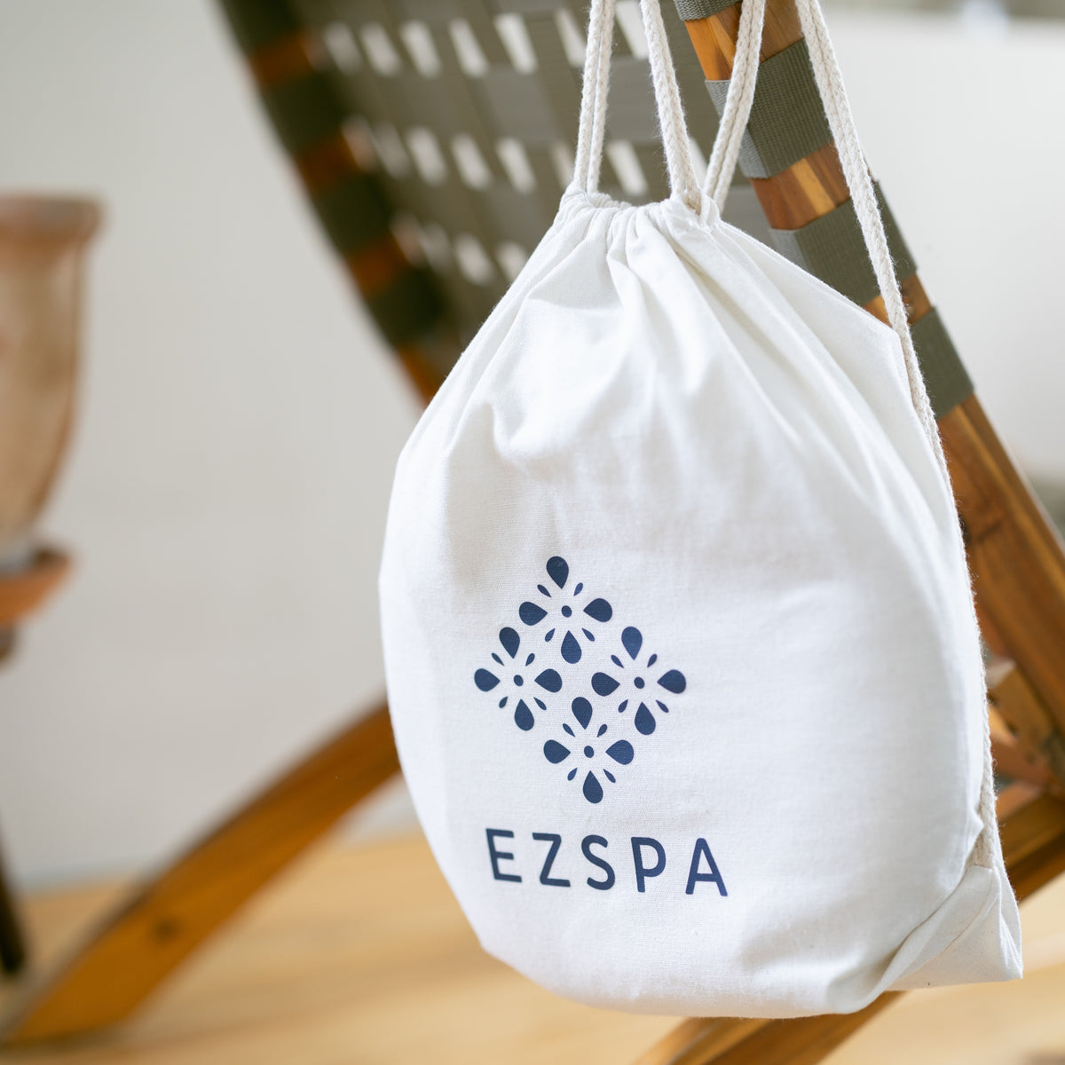 La bolsa de transporte de algodón de Ezspa con el logotipo, colgada de una silla