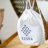 La bolsa de transporte de algodón de Ezspa con el logotipo, colgada de una silla