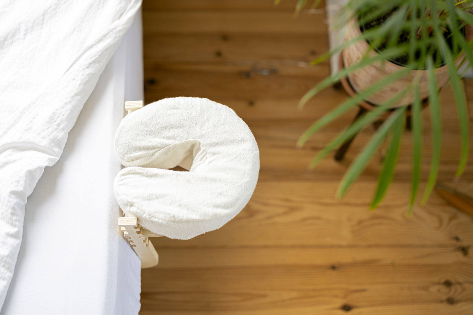 El Set de masaje Ezspa al borde de una cama hecha, sobre un suelo de madera